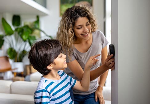 Mother and son adjusting thermostat