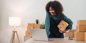 Business owner holding boxes while working on a computer